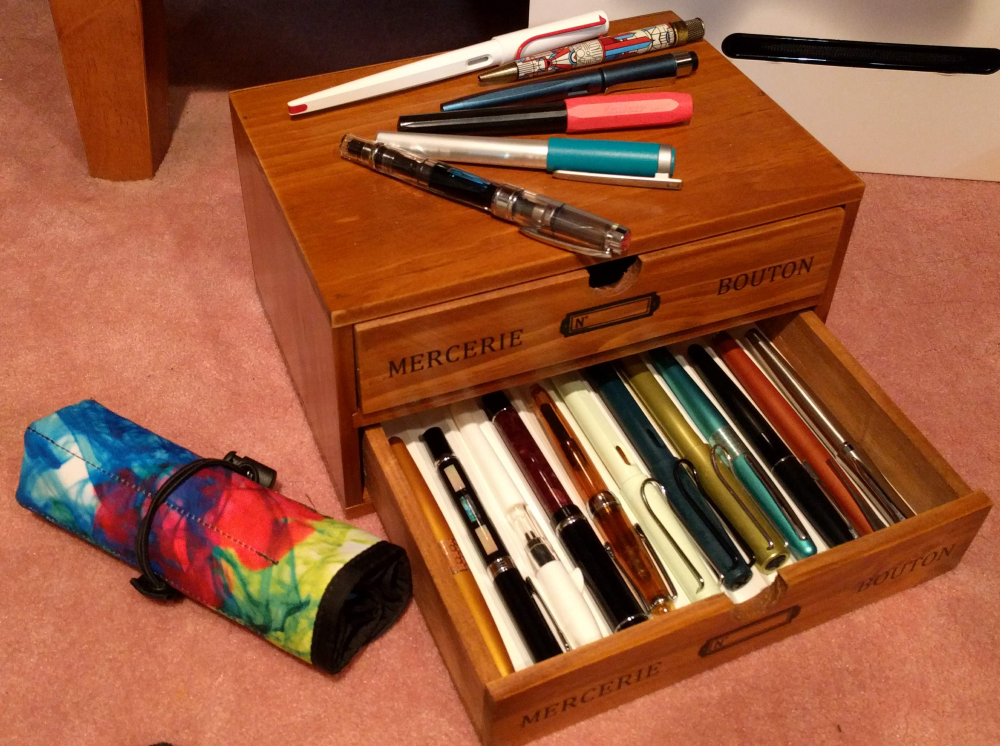 a box of fountain pens next to a pen wrap